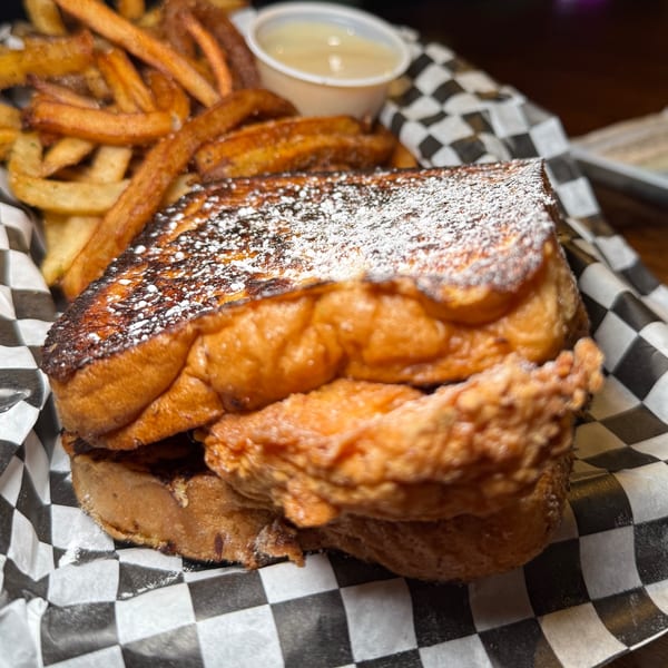 SideChick HTX's fried chicken sandwich on French toast, dusted with powdered sugar, served with fries.