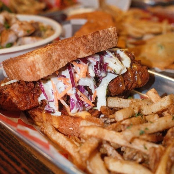 SideChick HTX fried chicken sandwich with coleslaw and fries on a metal tray.