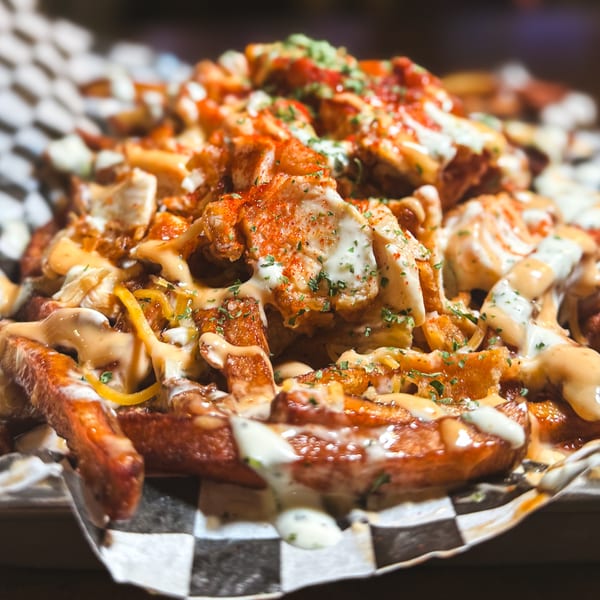 SideChick HTX's loaded fries, topped with fried chicken pieces, various sauces, and seasonings.